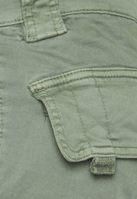 Olivengrønne cargo-shorts med en stor klaftlomme, tekstureret stof og forstærkede sømme. Indeholder en ekstra løkke.