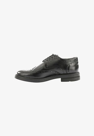 Scarpa da uomo in pelle nera con dettagli brogue, punta arrotondata e design con lacci; presenta una suola robusta e una texture liscia.