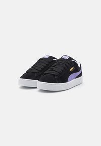 Baskets en daim noir avec accents violets, semelle en caoutchouc blanche et lacets plats noirs. Présente le logo PUMA sur la languette et le panneau latéral.