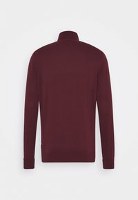 Pull en bourgogne, en tissu tricoté doux, manches longues, col montant, bords côtelés aux poignets et à l'ourlet, design uni sans motifs ni accents.