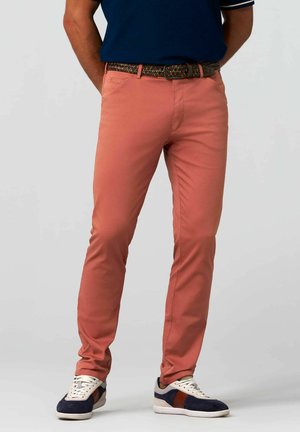 Pantalon en tissu coton rose corail avec une coupe ajustée, doté de poches avant et arrière. Accompagné d'une ceinture tissée multicolore et de baskets.
