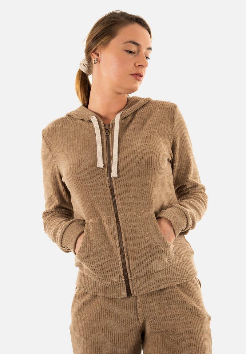 Sudadera con cremallera de color marrón y con superficie acanalada, que presenta una capucha con cordón, bolsillos frontales y puños ajustados. Se combina con pantalones a juego.