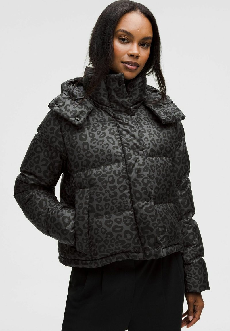 Jachetă puffer neagră cu un design capitonat în imprimeu de leopard, guler înalt și nasturi mari. Are o siluetă scurtă și buzunare laterale.