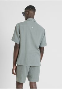 Korte mouwen overhemd en shorts set in lichtgroen textiel. Heeft een ontspannen pasvorm, een omgeslagen kraag en een subtiel logo op de achterkant.