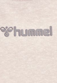 logo hummel en gris sur tissu beige, avec une icône d'abeille stylisée à côté du nom de la marque en minuscules