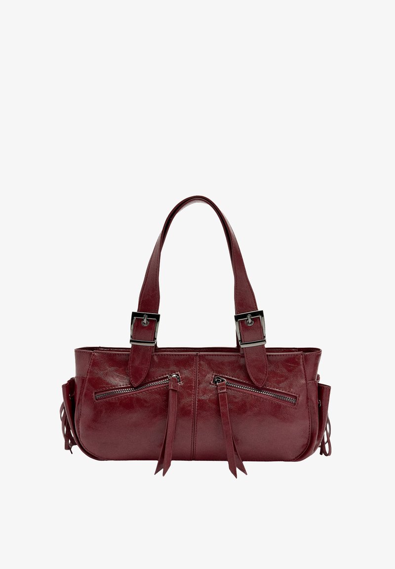 Butelkowa skórzana torebka z dwoma kieszeniami na zamek, ozdobiona frędzlami, z dwoma uchwytami. Charakteryzuje się gładką teksturą i prostokątnym kształtem.