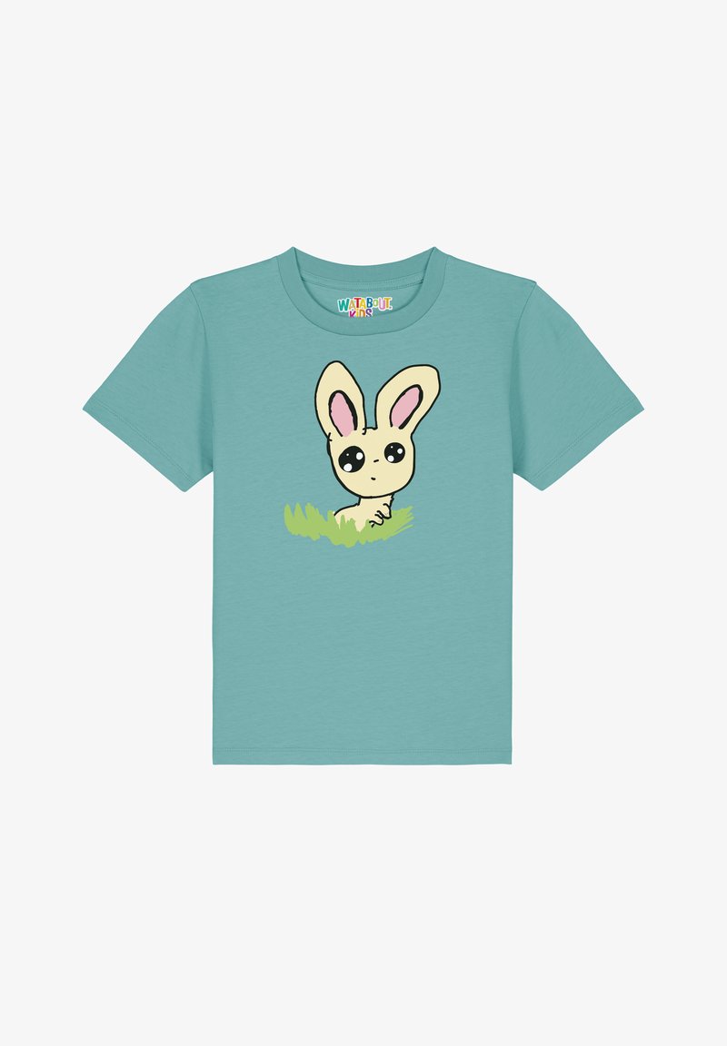 Hellblaues T-Shirt mit kurzen Ärmeln, das einen Cartoon-Hasen mit großen Augen und rosa Ohren zeigt, vor grünem Gras. Aus Baumwolle.