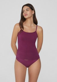 Fioletowa koszulka na ramiączkach z cienkimi paskami i dopasowanym krojem, w zestawie z pasującym bikini. Miękka tkanina z minimalną ilością szwów i bez widocznych wzorów czy akcentów.