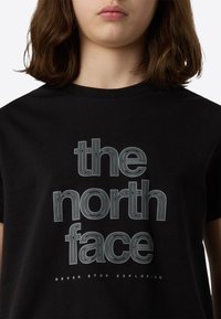 Črna bombažna majica s kratkimi rokavi, na kateri je bel napis z obrisom: »the north face« v ukrivljeni zasnovi, pod katerim je napis »NEVER STOP EXPLORING».