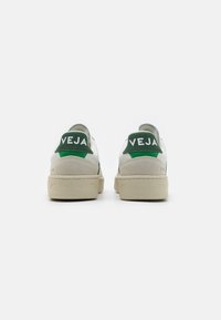 Baskets blanches avec des accents verts et le logo "VEJA" sur le talon. Confectionnées en cuir et daim, avec une semelle texturée.