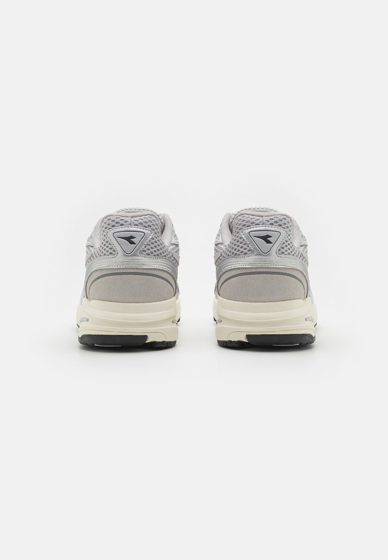Grijze sport schoenen gemaakt van mesh en suede, met een afgeronde vorm, een contrasterende crèmekleurige tussenzool en een driehoekig logo aan de achterkant.