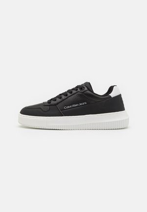 Sneaker in pelle nera con suola in gomma bianca, punta tonda e design con lacci. Presenta il logo del marchio e accenti a contrasto sul tallone.