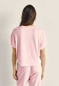 Lichtroze, T-shirt met korte mouwen, gemaakt van zachte stof, met een ontspannen pasvorm en een ronde halslijn, gecombineerd met bijpassende broeken.