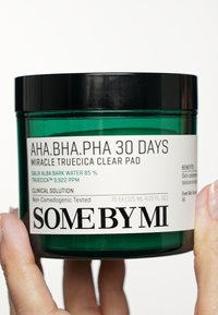 Pot vert étiqueté "AHA.BHA.PHA 30 Days Miracle Truecica Clear Pad" avec un couvercle noir ; contient 70 pads, 125 mL, détails de la solution clinique visibles.