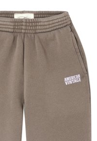 Bruine joggingbroek van zachte stof, met een geribbelde tailleband en een wit "AMERICAN VINTAGE"-logo op de linker dij.