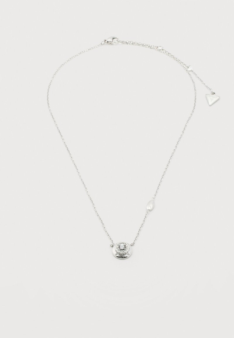 Collier délicat en chaîne argentée avec un pendentif circulaire orné d'une pierre précieuse claire centrale et un petit charme triangulaire près du fermoir.