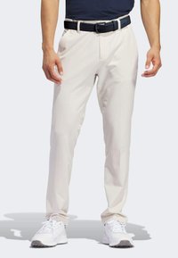 Light beige pants with a straight-leg design, featuring two side pockets and a braided navy belt. Worn with white sneakers.