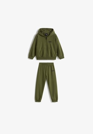 Olivgrüner Kinder-Trainingsanzug mit Reißverschluss-Hoodie und Jogginghose mit elastischem Bund, beide mit kleinem schwarzem Logo auf Brust und Bein.