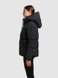 Svart puffjacka med huva, boxig design, stora vadderade sektioner, dragkedjeförsedd sidoficka och en logotypdetalj på nederkanten.