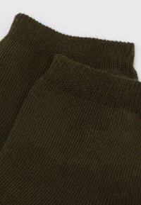 Dunkelgrüne gerippte Stricksocken mit weicher Textur und umgeschlagenem oberen Rand, die eine feine Webart und ein einheitliches Muster aufweisen.
