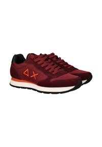 Un paio di sneaker sportive color bordeaux con lacci e loghi arancioni, colletto del tallone nero, intersuole bianche e suole nere su uno sfondo bianco.