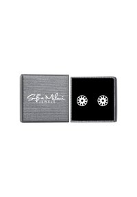 Sölvpresentask med en strukturerad yta, innehållande runda vita öronstift med ett geometriskt mönster. Perfekt för att ge bort.