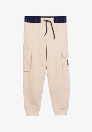 Pantaloni jogger cargo beige con vita elasticizzata blu navy, coulisse, tasche con patta ai lati, polsini a coste e una piccola toppa bianca e nera sulla tasca sinistra.