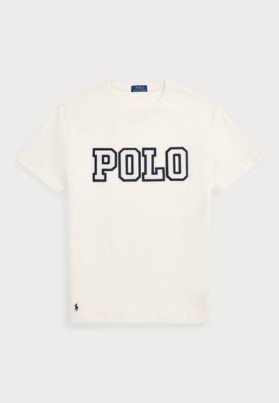 White cotton t-shirt featuring "POLO" in large navy letters across the chest, with a small navy logo on the hem. Classic crew neck design.