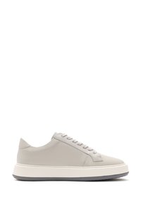 Baskets en cuir gris clair au design bas, avec un bout rond, des lacets plats et une semelle en caoutchouc blanc épaisse. Présente une texture lisse et un minimalisme dans les détails.