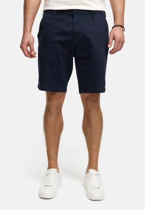 Navy blue chino shorts made from cotton, featuring belt loops, side pockets, and a clean finish at the hem, paired with white sneakers.