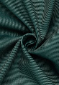 Getextureerde teal stof met een geribbelde patroon, die een glad oppervlak toont dat aan de randen krult, waardoor de diepte en visuele complexiteit worden benadrukt.