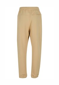Beige sporta bikses ar elastīgu jostu, sānu kabatām un sašaurinātiem potītes galiem. Izgatavotas no mīksta, gluda auduma ar vienkāršu dizainu.