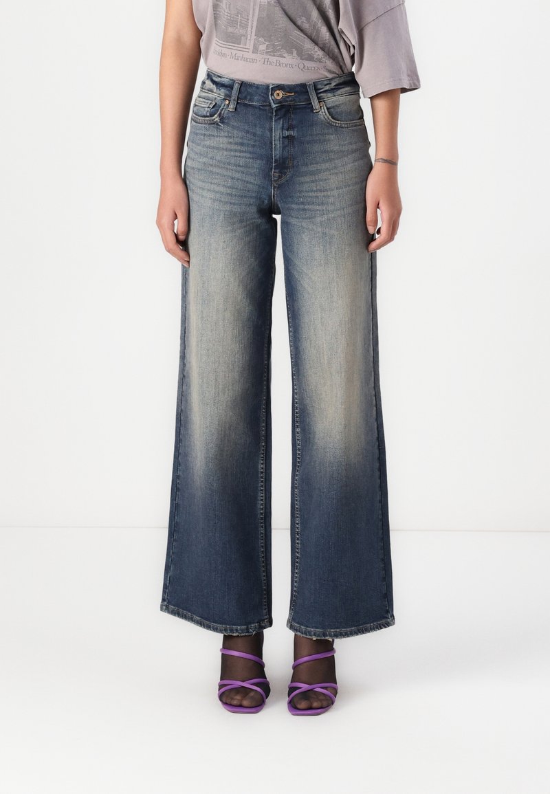Jean denim à jambes larges avec une teinte bleue délavée, taille haute, doté d'une fermeture à boutons à l'avant et d'un design classique à cinq poches.
