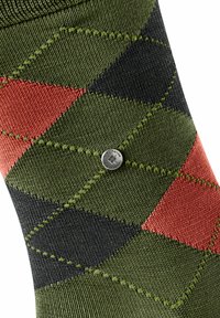 Skarpety w wzór argyle z zielonymi, czarnymi i czerwonawo-pomarańczowymi diamentami. Zawierają mały, srebrny metalowy element z logo.