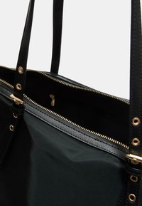 Borsa a tracolla nera con corpo in tessuto liscio, chiusura con zip dorata e fasce sottili; presenta una sezione superiore nera strutturata.