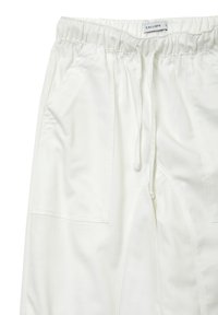 Pantalons de jogging blancs avec une taille élastique, cordon de serrage et poches avant ; texture lisse ; design minimaliste avec des lignes épurées.