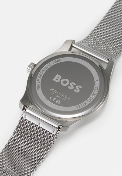 Montre en acier inoxydable argenté avec un dos lisse, un bracelet en maille et un logo "BOSS" gravé. Résistante à l'eau jusqu'à 3 bars.