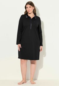 Vestido negro de manga larga con tapa de botones, cuello de satén y aberturas laterales, hecho de una tela suave. Diseño sencillo, corte a la altura de la rodilla.