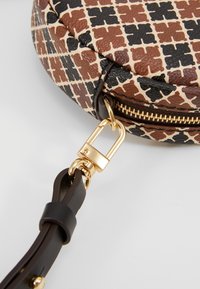 Runde Handtasche mit einer strukturierten, gemusterten Außenseite in Braun, Schwarz und Creme. Goldene Reißverschluss- und Hardwareakzente sowie ein dunkler Träger.