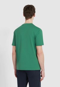 T-shirt verde a maniche corte in cotone, con scollatura rotonda, texture uniforme e design semplice senza motivi o dettagli.