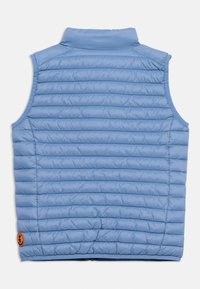 Ανοιχτό μπλε γιλέκο χωρίς μανίκια με καπιτονέ ύφασμα, όρθιο γιακά και μικρό στρογγυλό πορτοκαλί λογότυπο κοντά στο κάτω τελείωμα.