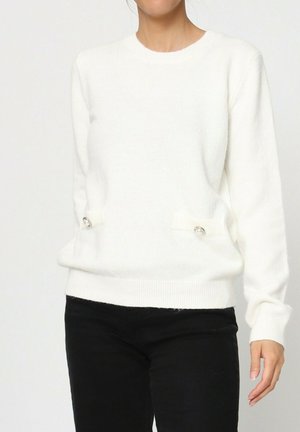 Pull en maille blanche avec un col rond, des manches longues et des accents décoratifs sur les côtés avec des boutons brillants. Texture douce et coupe décontractée.