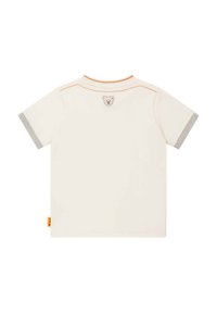 T-shirt crème à manches courtes avec des bords gris côtelés. Présente un accent de couture orange et un petit logo d'ours dans le dos. Tissu en coton doux.