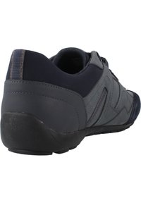 Chaussures de sport gris foncé avec une tige synthétique texturée, semelle en caoutchouc et accents bleus subtils. Dotées d'un design sans lacets et d'un talon rembourré.