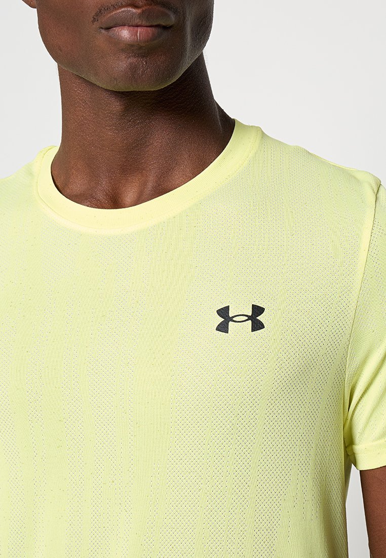 Maglia sportiva verde lime con tessuto testurizzato, scollatura a girocollo e logo Under Armour nero sul petto. Maniche corte.