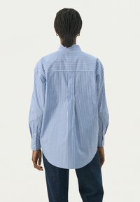 Blue and white striped button-up shirt with long sleeves, rounded hem, and cuffs. Made from lightweight fabric, featuring a pointed collar.