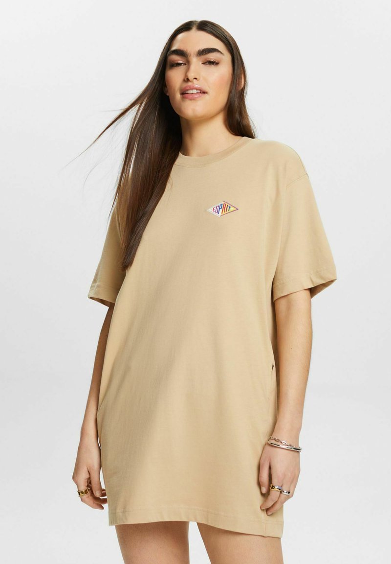 Beżowy, oversize t-shirt z krótkim rękawem i okrągłym dekoltem, z kolorowym logo w kształcie diamentu z napisem "ESPRIT" na piersi. Gładka tekstura materiału.