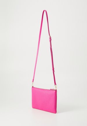 Petit sac bandoulière en cuir rose vif avec une sangle réglable et des détails de fermeture éclair dorés, suspendu sur un fond clair uni.