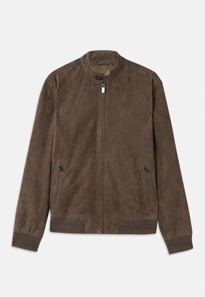 Jachetă din suede maro cu guler ridicat, două buzunare laterale cu fermoar și manșete ribbate. Textură netedă cu un design minimalist.