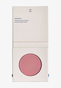 Rubor compacto en tono rosa claro, presentado en un estuche cuadrado crema con una superficie circular texturizada y elementos de diseño minimalistas.